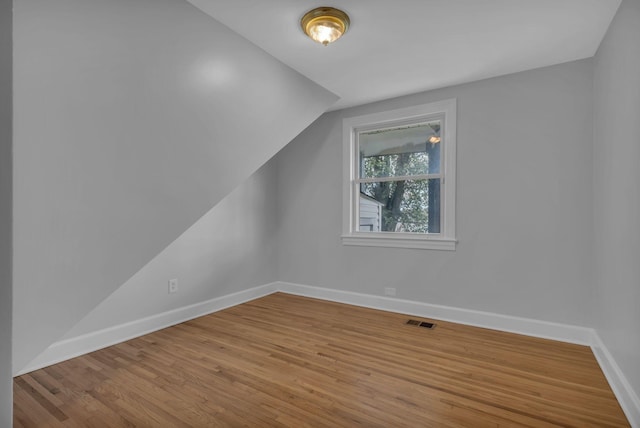 bonus room with hardwood / wood-style floors and vaulted ceiling