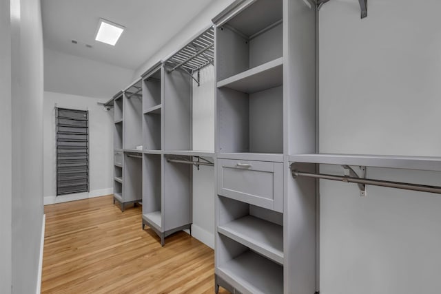 walk in closet with light hardwood / wood-style flooring