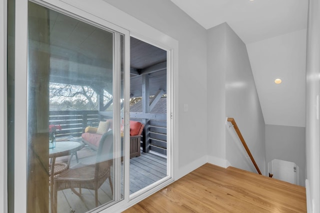 doorway to outside featuring lofted ceiling, radiator, and wood-type flooring