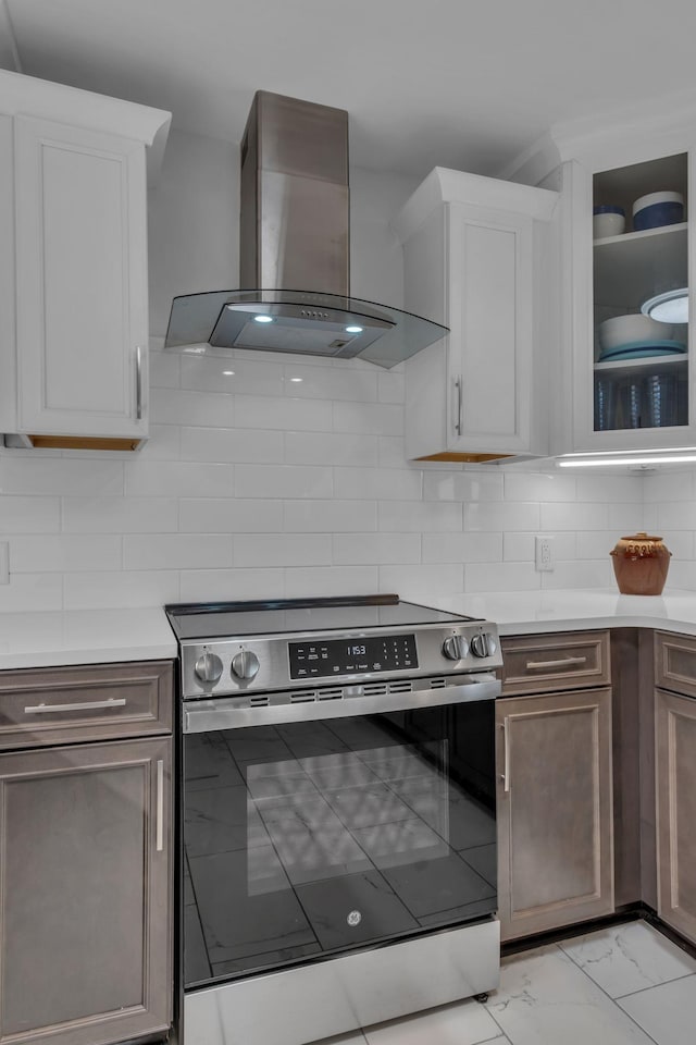 kitchen with white cabinetry, ventilation hood, stainless steel electric range, and backsplash