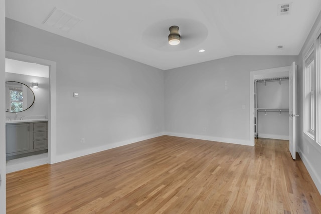 unfurnished bedroom featuring vaulted ceiling, light wood-type flooring, a closet, ceiling fan, and multiple windows