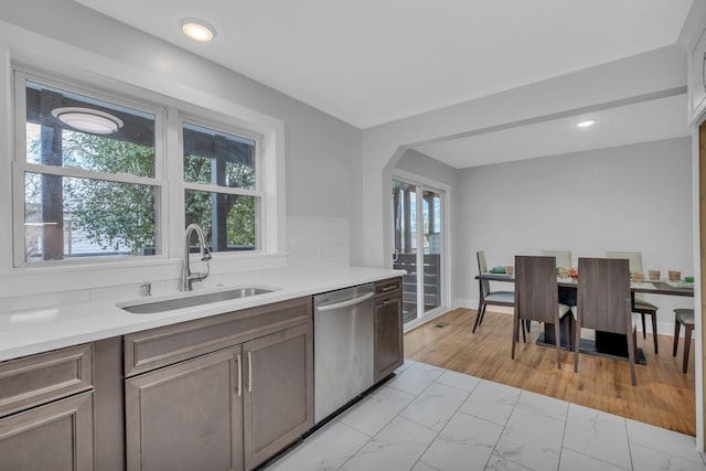 kitchen featuring stainless steel dishwasher, sink, and dark brown cabinets