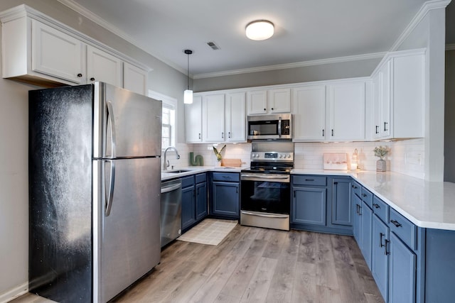 kitchen with blue cabinetry, white cabinetry, light hardwood / wood-style flooring, pendant lighting, and stainless steel appliances