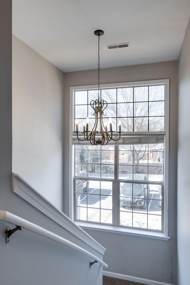 stairway featuring a chandelier and carpet