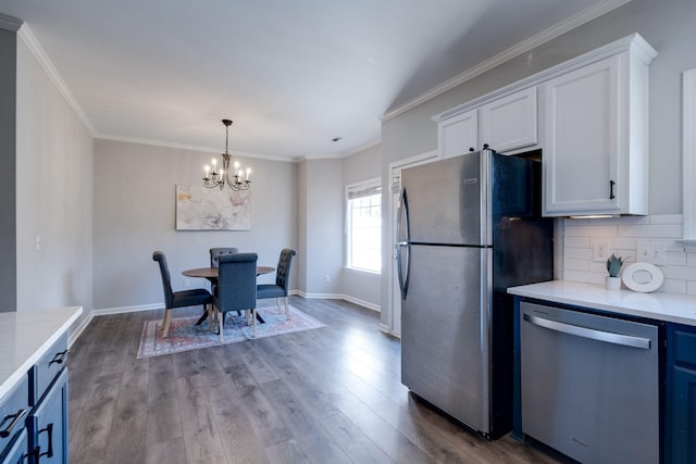 kitchen with appliances with stainless steel finishes, hardwood / wood-style floors, white cabinets, backsplash, and ornamental molding