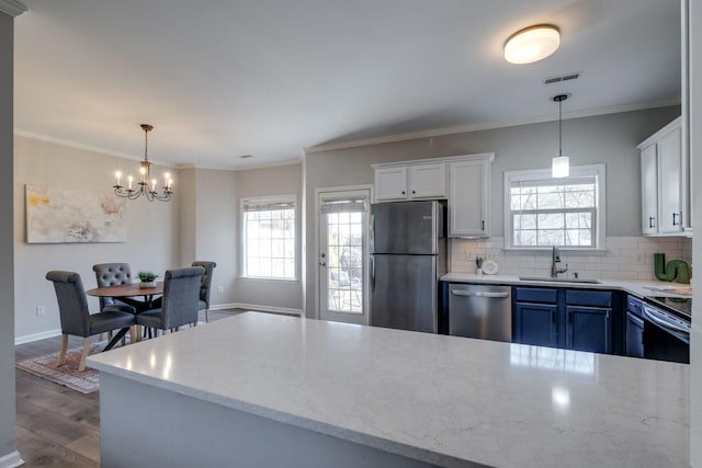 kitchen with appliances with stainless steel finishes, decorative light fixtures, sink, white cabinets, and backsplash