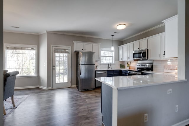 kitchen featuring hanging light fixtures, appliances with stainless steel finishes, white cabinets, and kitchen peninsula