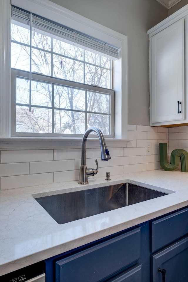 kitchen featuring tasteful backsplash, white cabinetry, sink, light stone counters, and blue cabinetry