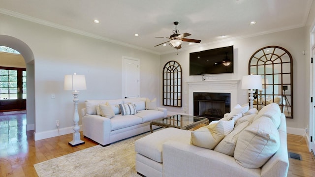 living room with light hardwood / wood-style flooring, ornamental molding, and ceiling fan