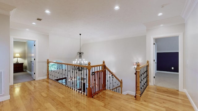 hall featuring ornamental molding, light hardwood / wood-style flooring, and a notable chandelier