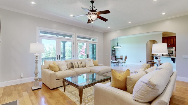 living room with ceiling fan, ornamental molding, and light hardwood / wood-style flooring