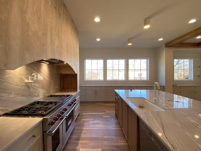 kitchen featuring sink, double oven range, dishwasher, light stone countertops, and backsplash