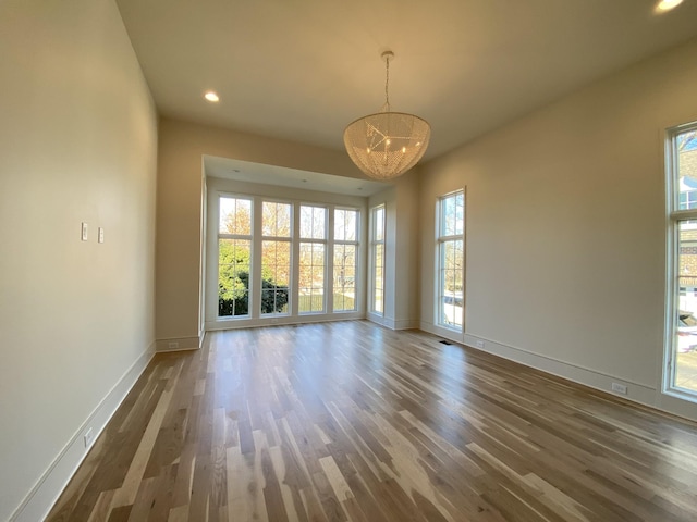 empty room with dark hardwood / wood-style flooring and a notable chandelier