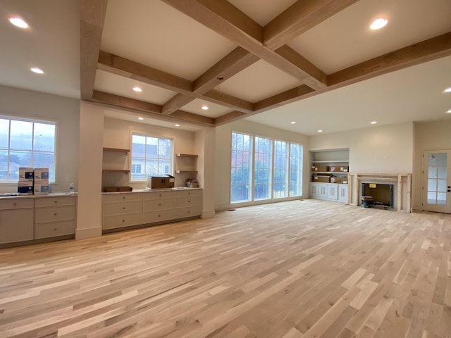 unfurnished living room with coffered ceiling, beam ceiling, and light hardwood / wood-style flooring