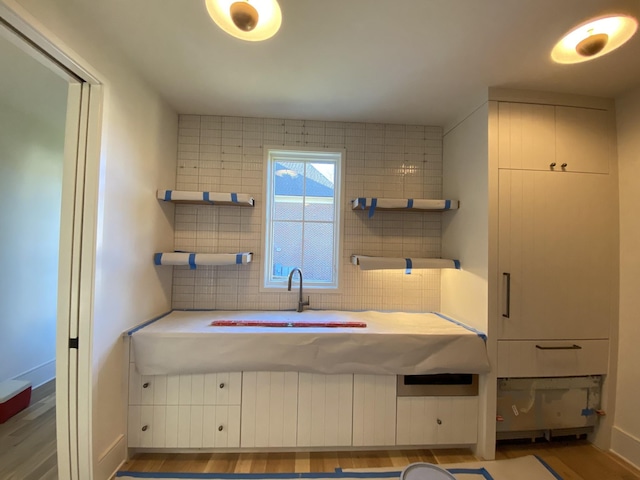 bathroom with hardwood / wood-style flooring, sink, and decorative backsplash