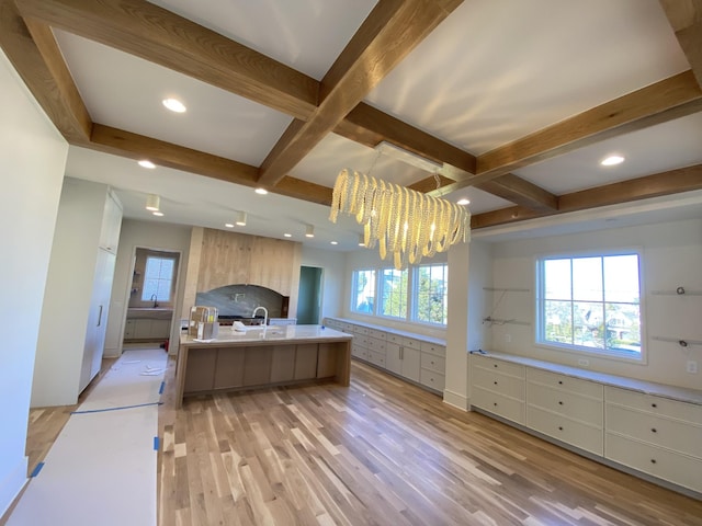 kitchen featuring sink, light hardwood / wood-style flooring, a notable chandelier, pendant lighting, and a kitchen island with sink