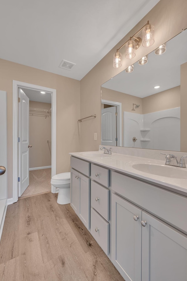 bathroom with hardwood / wood-style flooring, vanity, a shower, and toilet