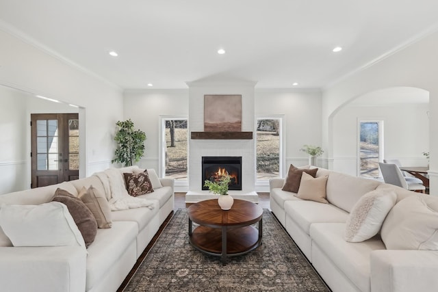 living room featuring crown molding, a large fireplace, a healthy amount of sunlight, and french doors