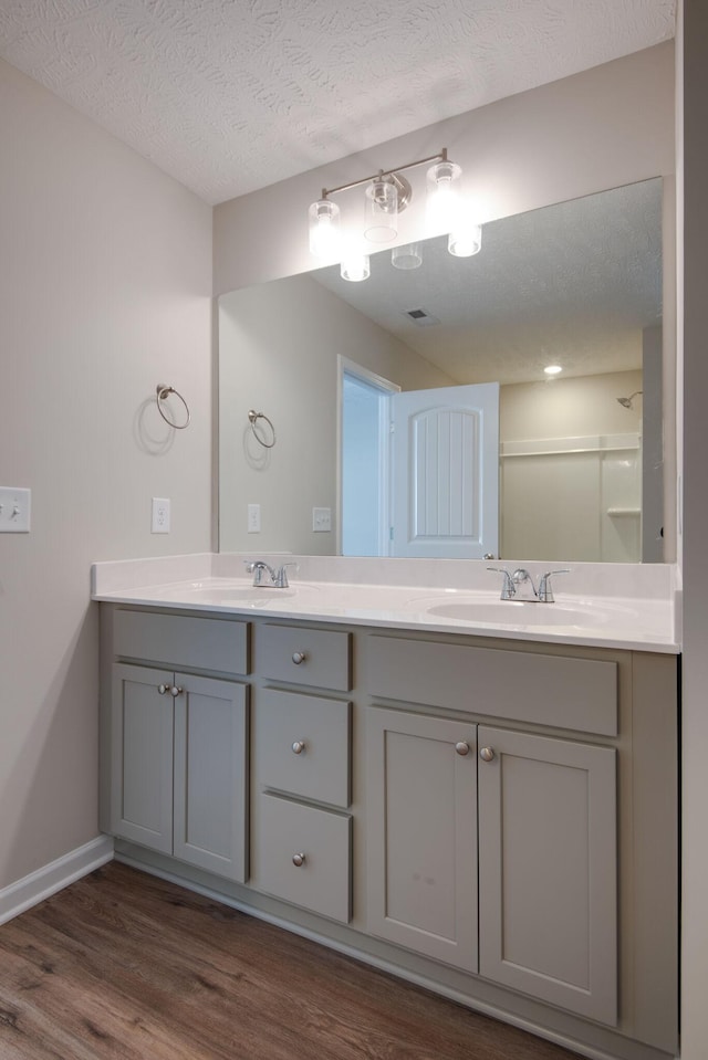 bathroom with vanity, hardwood / wood-style floors, a textured ceiling, and walk in shower