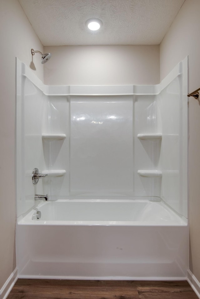 bathroom featuring hardwood / wood-style flooring, tub / shower combination, and a textured ceiling