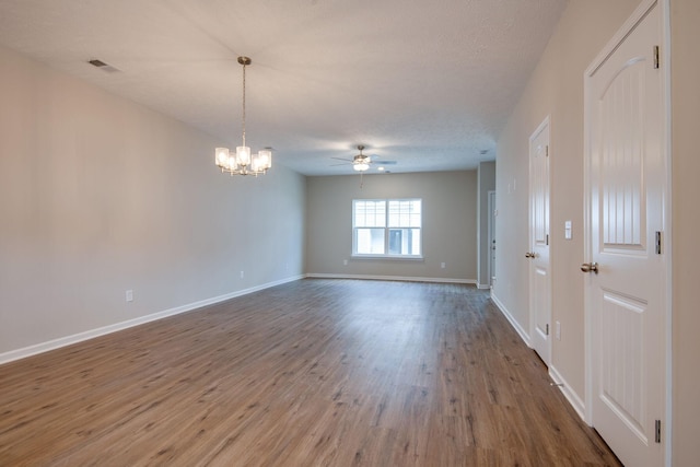 spare room featuring hardwood / wood-style flooring, ceiling fan with notable chandelier, and a textured ceiling