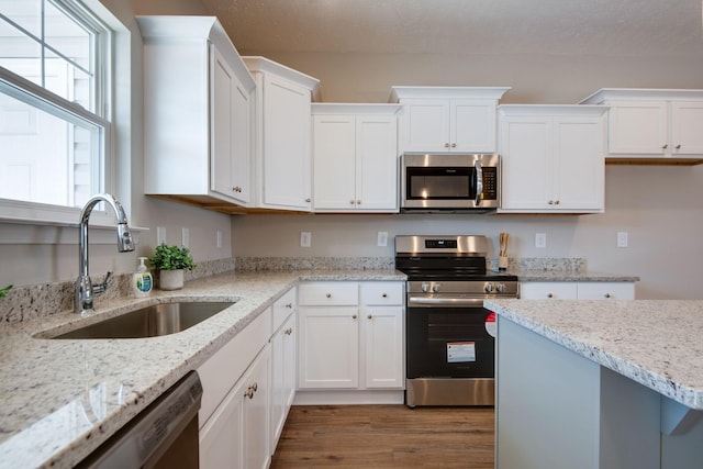 kitchen featuring white cabinetry, sink, light stone countertops, and appliances with stainless steel finishes