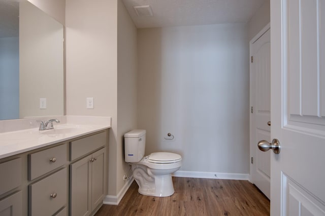 bathroom featuring hardwood / wood-style flooring, vanity, toilet, and a textured ceiling