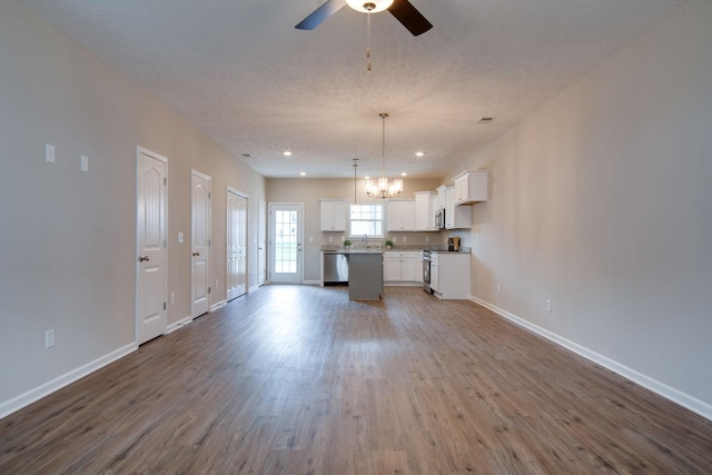 kitchen featuring hardwood / wood-style floors, decorative light fixtures, white cabinets, a center island, and stainless steel appliances