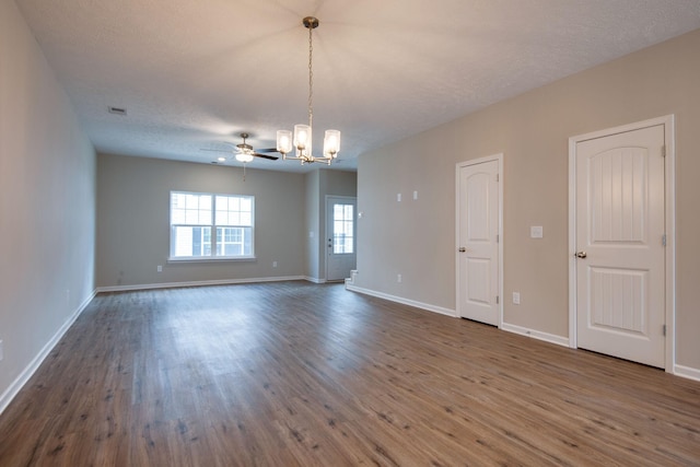 empty room with dark hardwood / wood-style flooring, ceiling fan with notable chandelier, and a textured ceiling