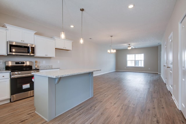 kitchen featuring a kitchen island, decorative light fixtures, white cabinets, a kitchen bar, and stainless steel appliances