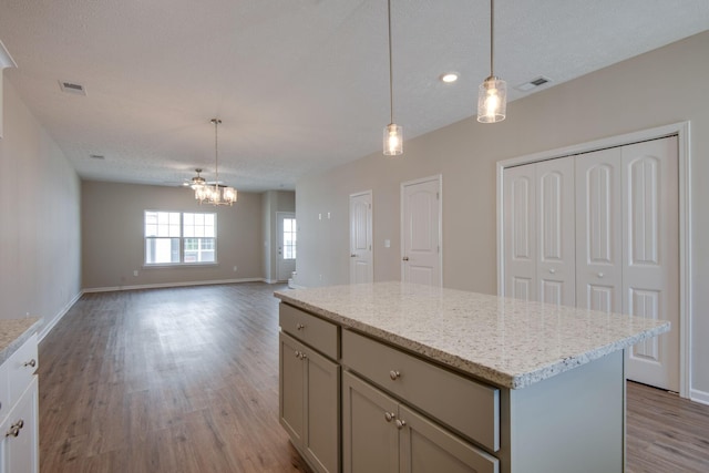 kitchen featuring decorative light fixtures, a center island, a textured ceiling, and light wood-type flooring