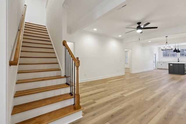 interior space with ornamental molding, beam ceiling, ceiling fan with notable chandelier, and wood-type flooring