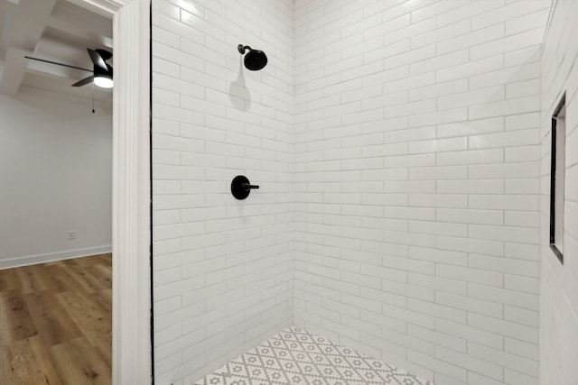 bathroom featuring hardwood / wood-style flooring, a tile shower, and ceiling fan