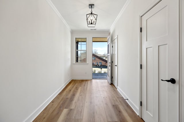 hall with a notable chandelier, crown molding, and light hardwood / wood-style flooring