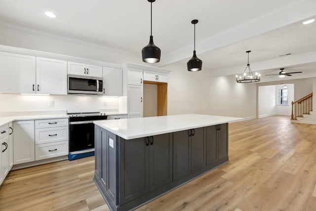 kitchen featuring a kitchen island, pendant lighting, white cabinets, and electric stove