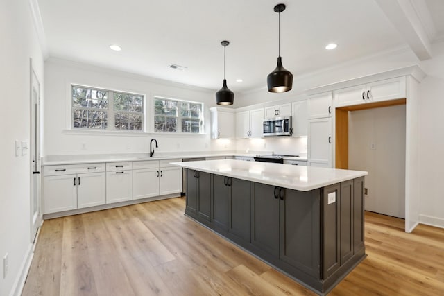 kitchen featuring decorative light fixtures, a center island, light wood-type flooring, and white cabinets