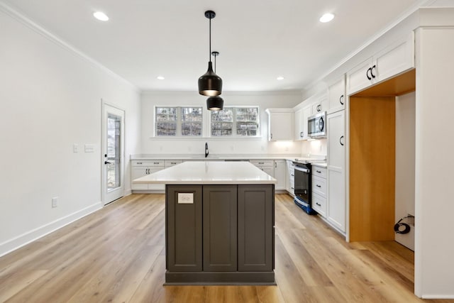 kitchen featuring white cabinets, hanging light fixtures, ornamental molding, a center island, and electric range