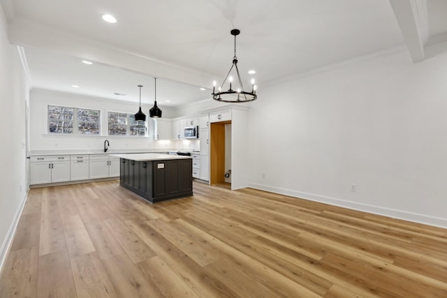 kitchen featuring crown molding, white cabinetry, light hardwood / wood-style floors, a kitchen island, and decorative light fixtures