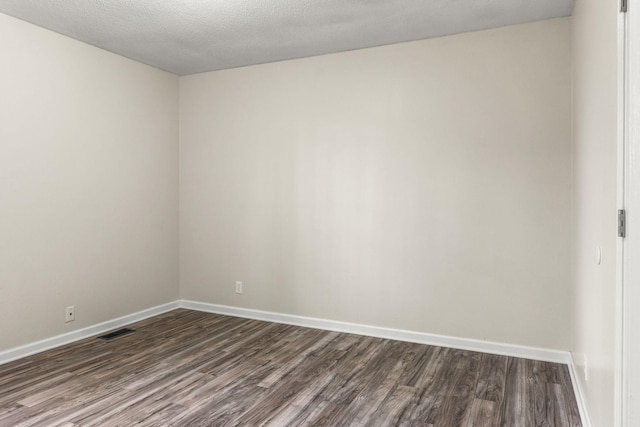 spare room with dark hardwood / wood-style flooring and a textured ceiling