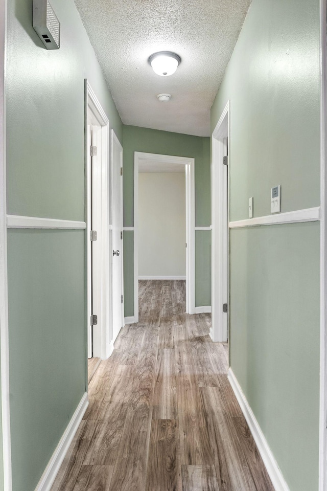 corridor featuring a textured ceiling and light wood-type flooring