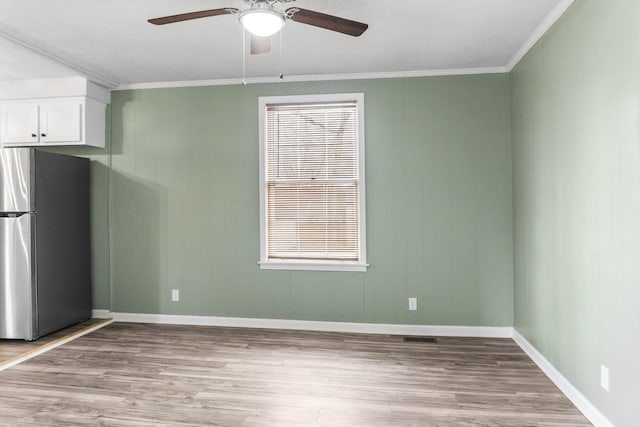 interior space with white cabinetry, crown molding, stainless steel refrigerator, and light wood-type flooring