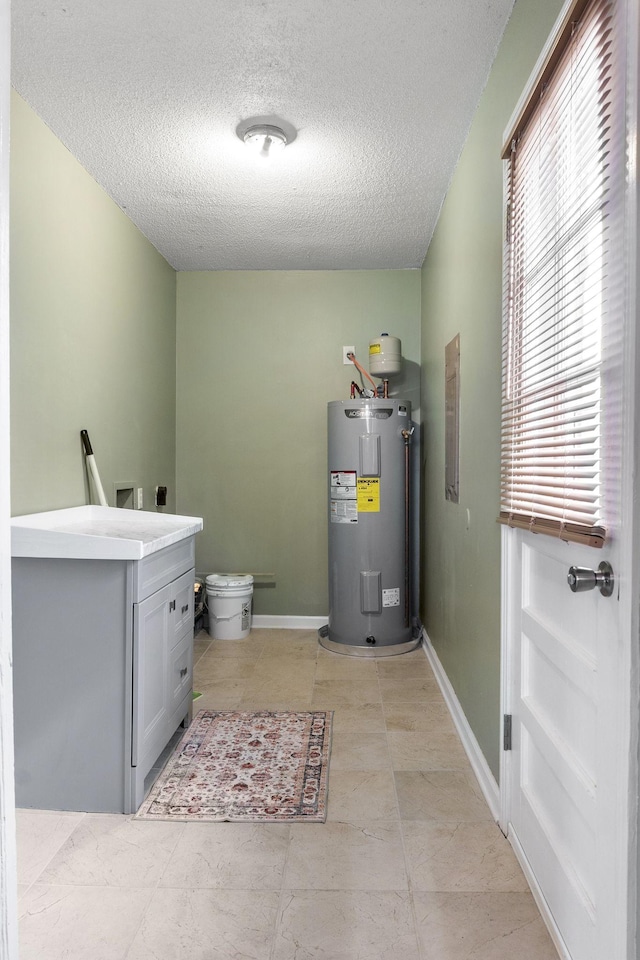 interior space with light tile patterned flooring, a textured ceiling, hookup for a washing machine, electric water heater, and electric dryer hookup