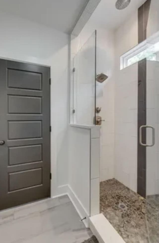 bathroom with marble finish floor and a stall shower