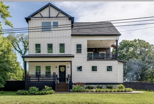 view of front of house featuring a balcony, covered porch, fence, board and batten siding, and a front yard