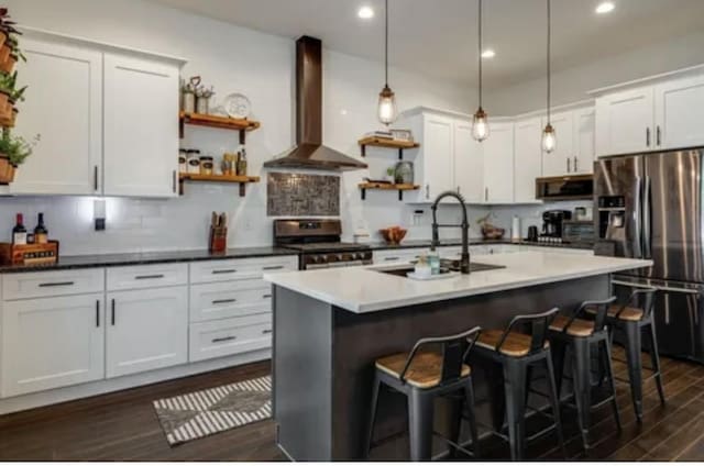 kitchen featuring open shelves, stainless steel appliances, backsplash, a sink, and wall chimney range hood