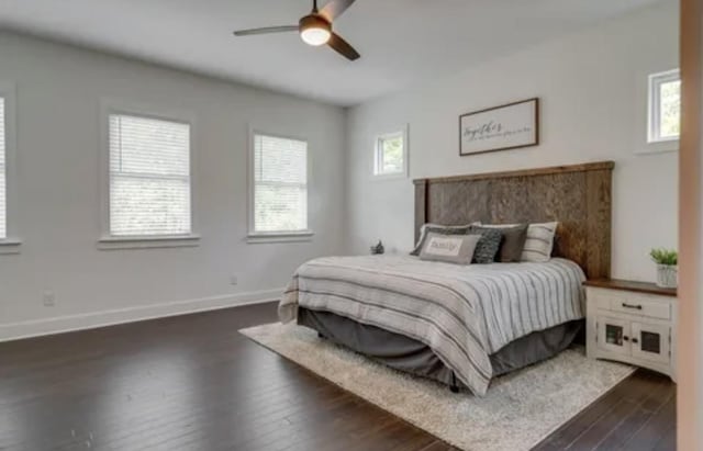 bedroom featuring dark wood-type flooring, multiple windows, baseboards, and a ceiling fan