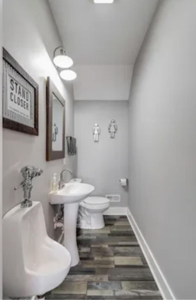 bathroom with wood finished floors, toilet, and baseboards