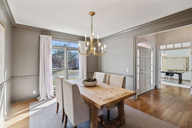 dining room with a notable chandelier, crown molding, and hardwood / wood-style flooring