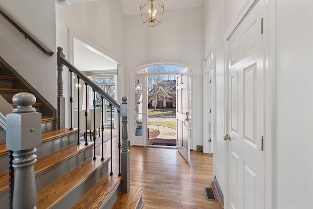 foyer with hardwood / wood-style floors, a towering ceiling, and a chandelier