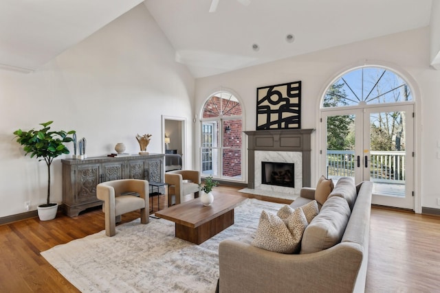 living room with plenty of natural light, hardwood / wood-style floors, lofted ceiling, and a high end fireplace